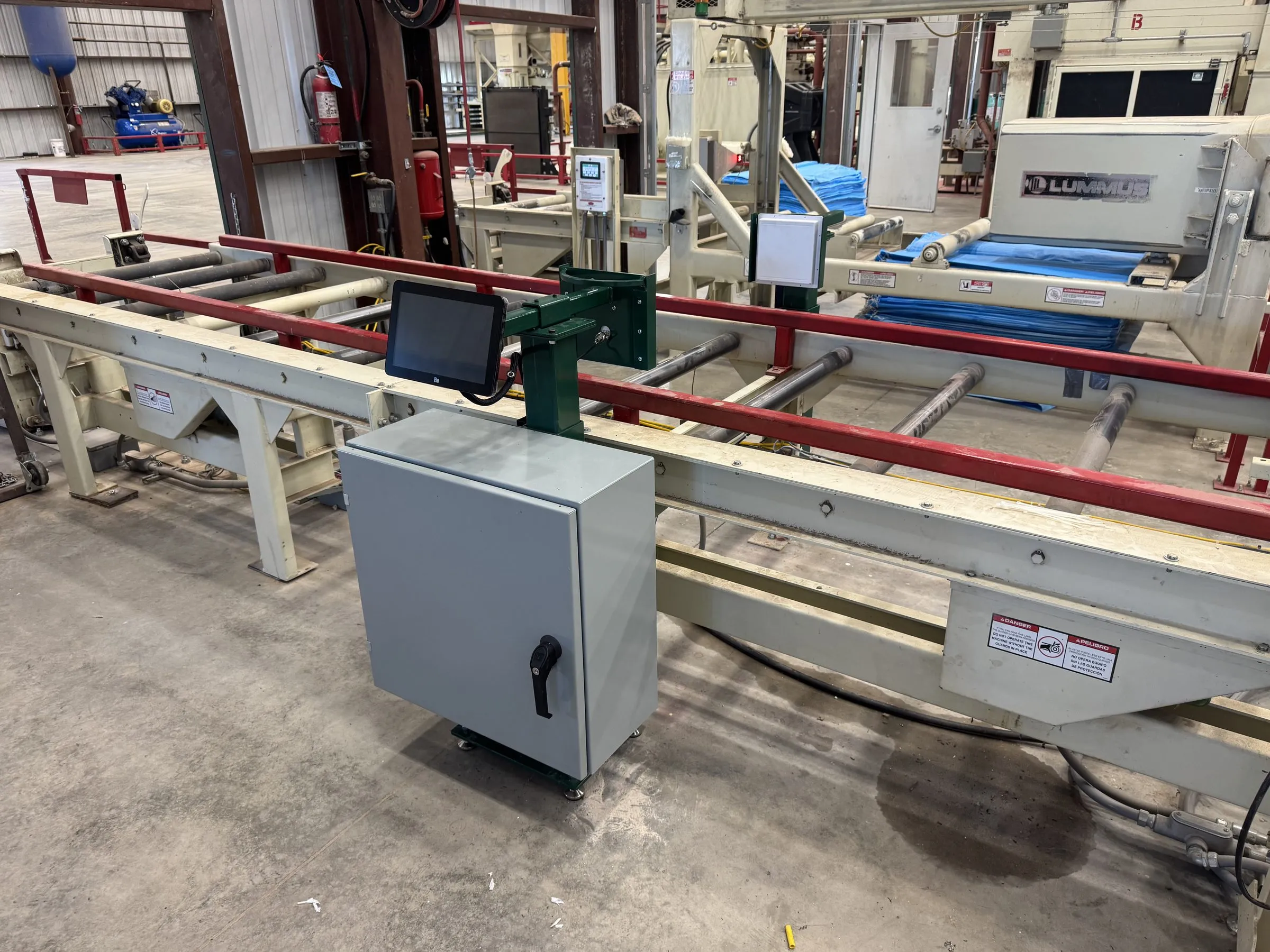 An MS-1 enclosure, sensor head and touchscreen installed alongside a bale conveyor, with a Lummus press behind
